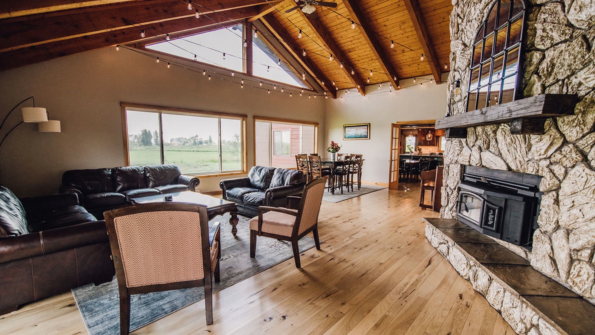 Great room with vaulted beams, stone fireplace, and string lights at Three Peaks Lodge