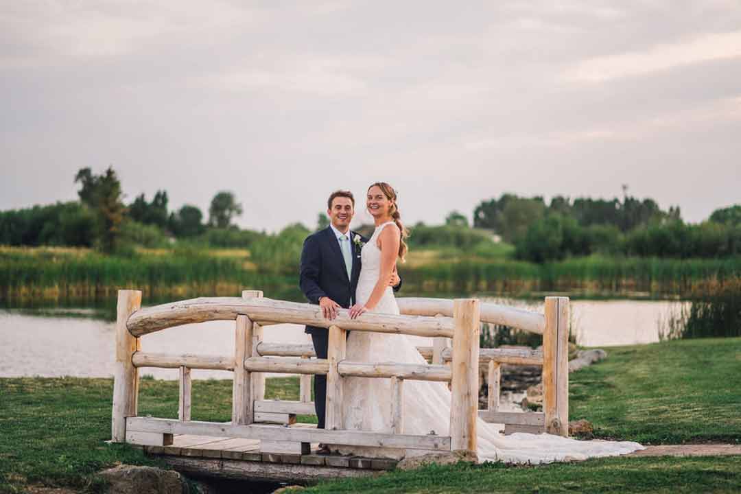 Bride and groom on the rustic bridge at Three Peaks